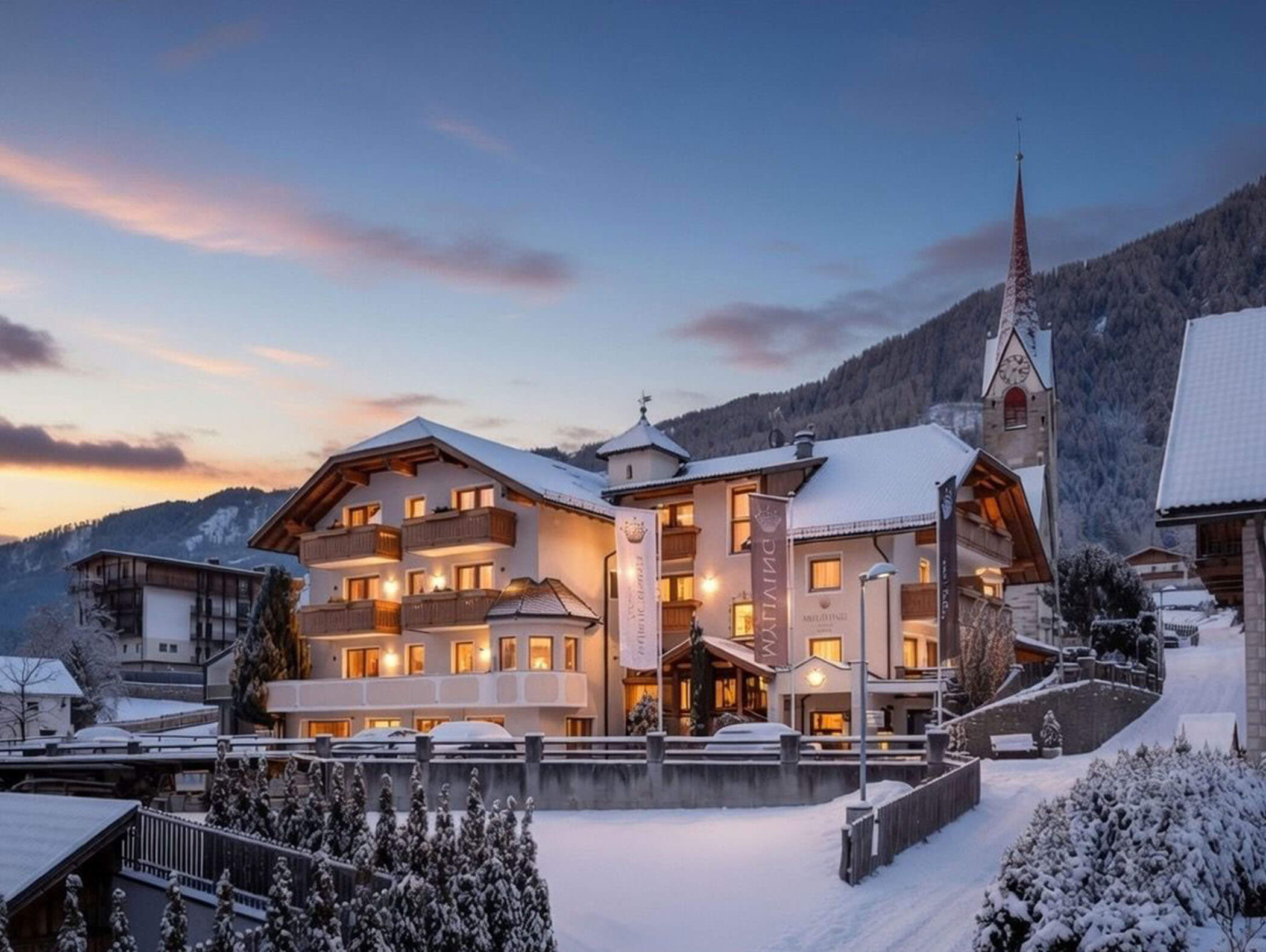 Schneebedecktes Alpendorf bei Sonnenuntergang mit einem beleuchteten Hotel und einem Kirchturm im Hintergrund. - Majestic Resorts (Relaunch)
