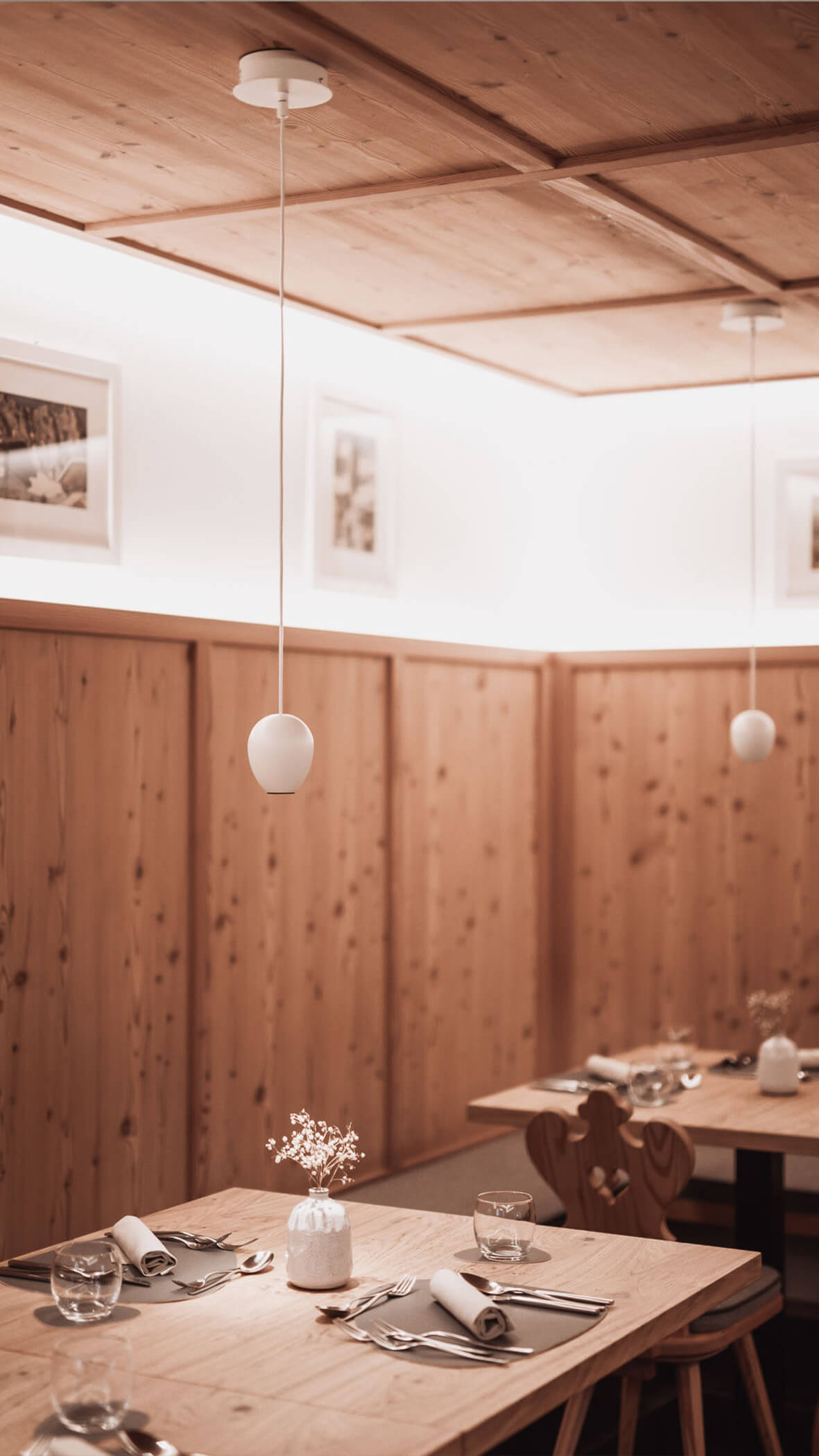 Gemütliches Holzrestaurant mit gedeckten Tischen, Hängelampen und minimalem Wanddekor. - Majestic Resorts (Relaunch)